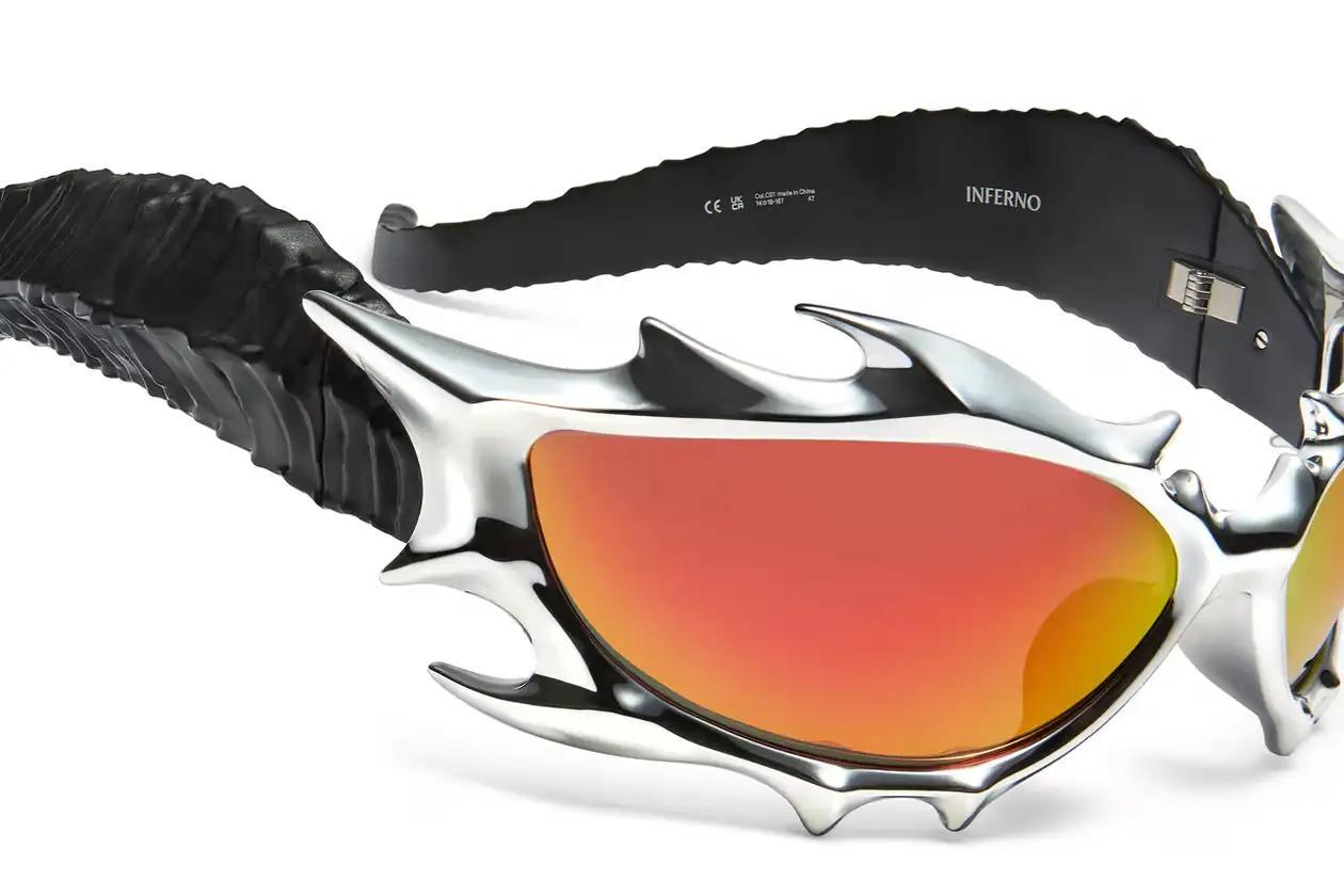 Gentle Monster x Tekken 8 Inferno goggles displayed on a dark background, showcasing red mirrored lenses and horn-like silver frames