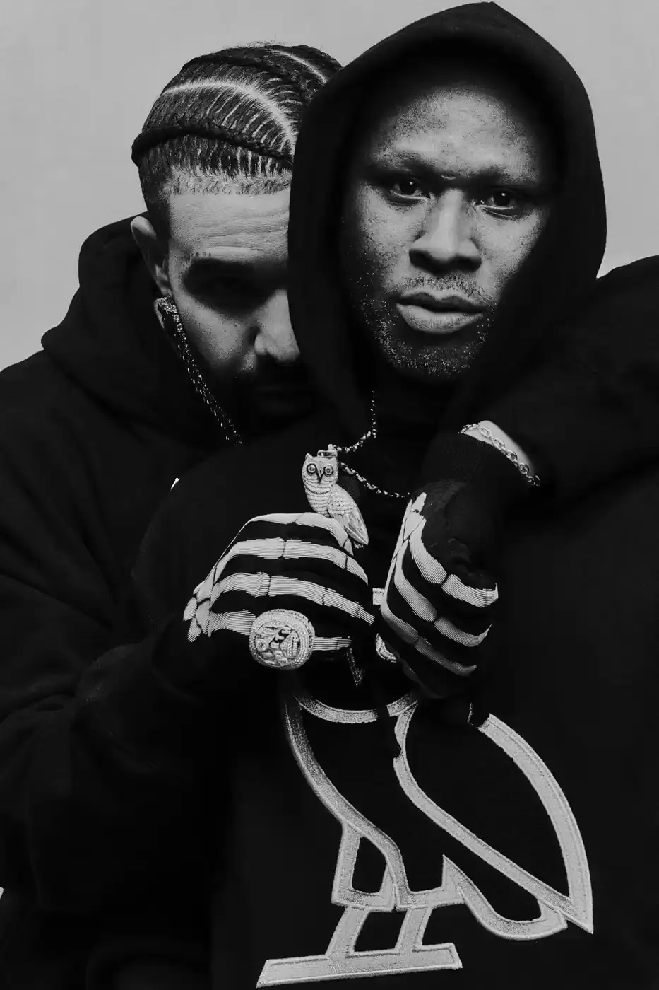 Drake and his OVO team members pose together wearing black hoodies with the OVO owl logo for the new "OG" campaign. The image shows Drake in the center, surrounded by his close associates including Jonny Roxx and Niko Carino. They stand against a plain background, emphasizing the group's unity and the branded clothing. Additional images feature individual shots of each team member modeling various pieces from the new OVO collection, including a letterman jacket and other sweater designs (image 5 of 7)