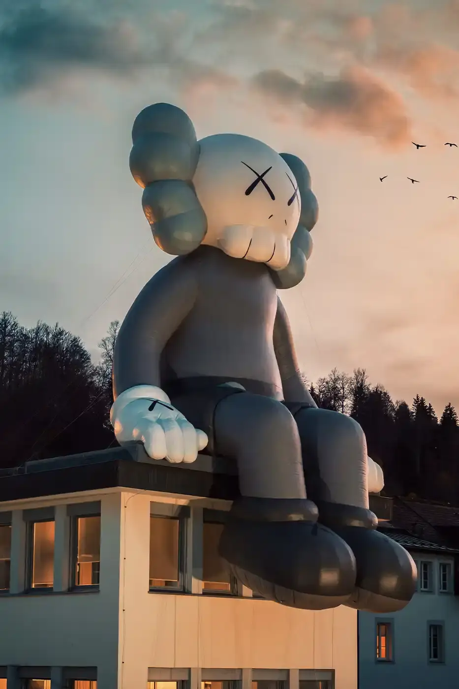 AllRightsReserved A massive 11-meter tall KAWS COMPANION sculpture in grey-toned color sits on the rooftop of the Audemars Piguet headquarters. The sculpture overlooks the glass spiral museum building in Le Brassus, Switzerland, against a mountainous backdrop, symbolizing the intersection of art and traditional watchmaking craftsmanship. (image 6 of 9)