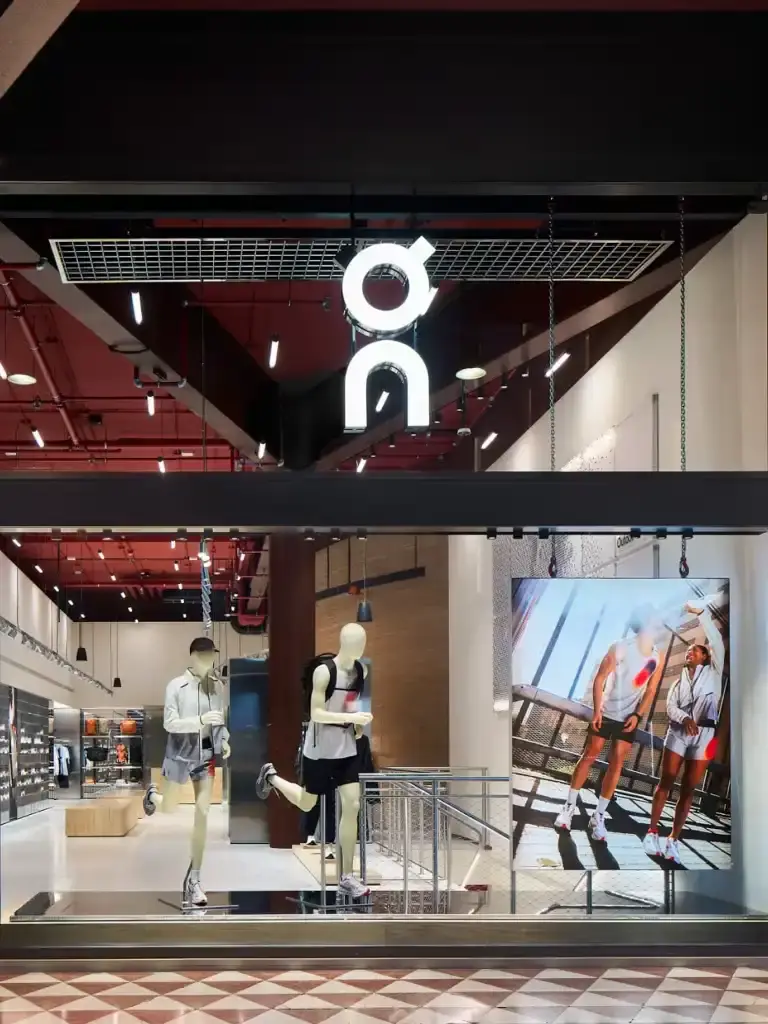 On, the Swiss sportswear brand, opens its first Italian flagship store in Milan's Corso Vittorio Emanuele II. The two-story, 480-square-meter store features innovative design by BBPR architects, including restored ceiling beams and a clay installation. It offers running gear, lifestyle products, and hosts community events. This opening marks On's significant expansion into the Italian market, blending Swiss engineering with Italian style in a prime fashion district location.