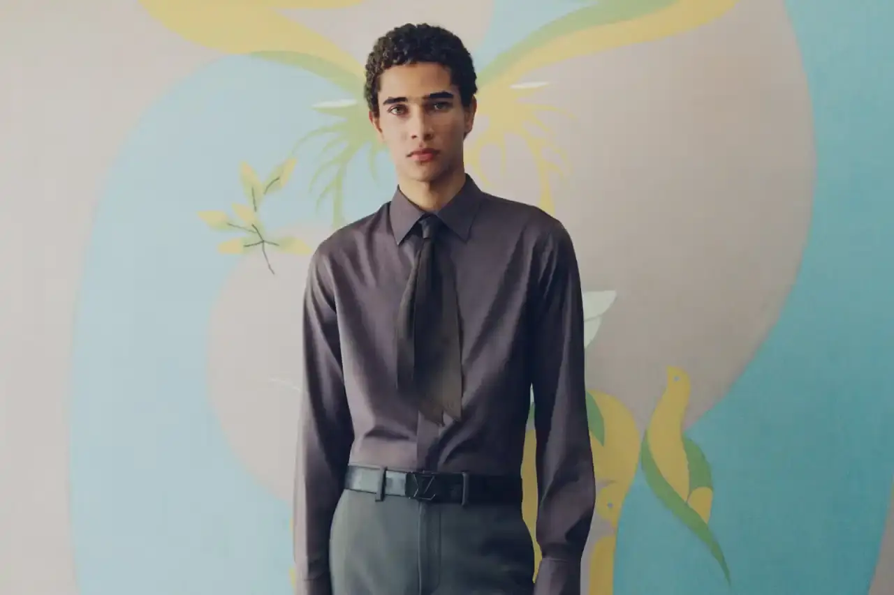Stef Mitchell Models wearing Louis Vuitton Spring 2025 collection pose in UNESCO's headquarters. They're dressed in earth-toned suits and casual wear, photographed in formal meeting rooms and gardens. The images showcase bags, sunglasses, and diplomatic-inspired fashion against modernist architecture. (image 15 of 15)