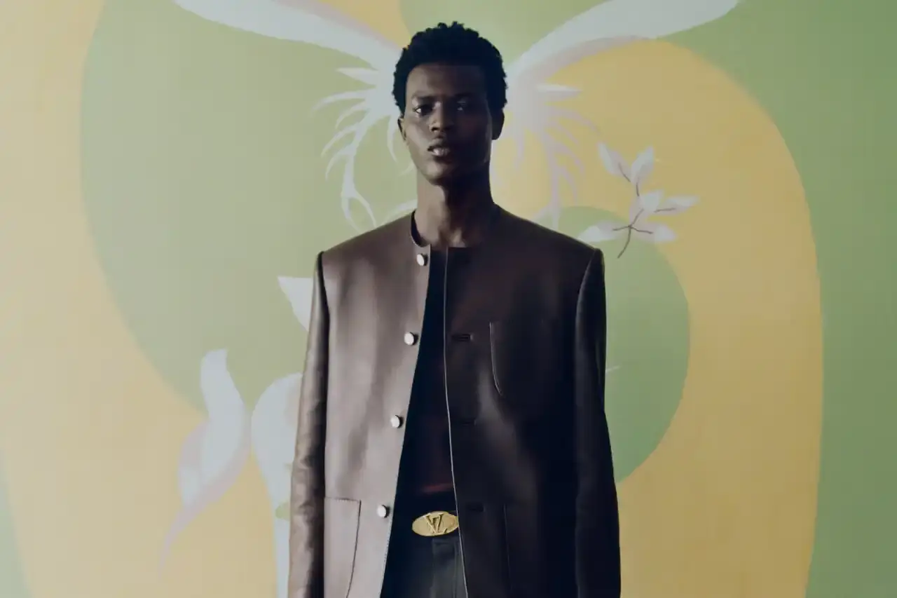 Stef Mitchell Models wearing Louis Vuitton Spring 2025 collection pose in UNESCO's headquarters. They're dressed in earth-toned suits and casual wear, photographed in formal meeting rooms and gardens. The images showcase bags, sunglasses, and diplomatic-inspired fashion against modernist architecture. (image 9 of 15)