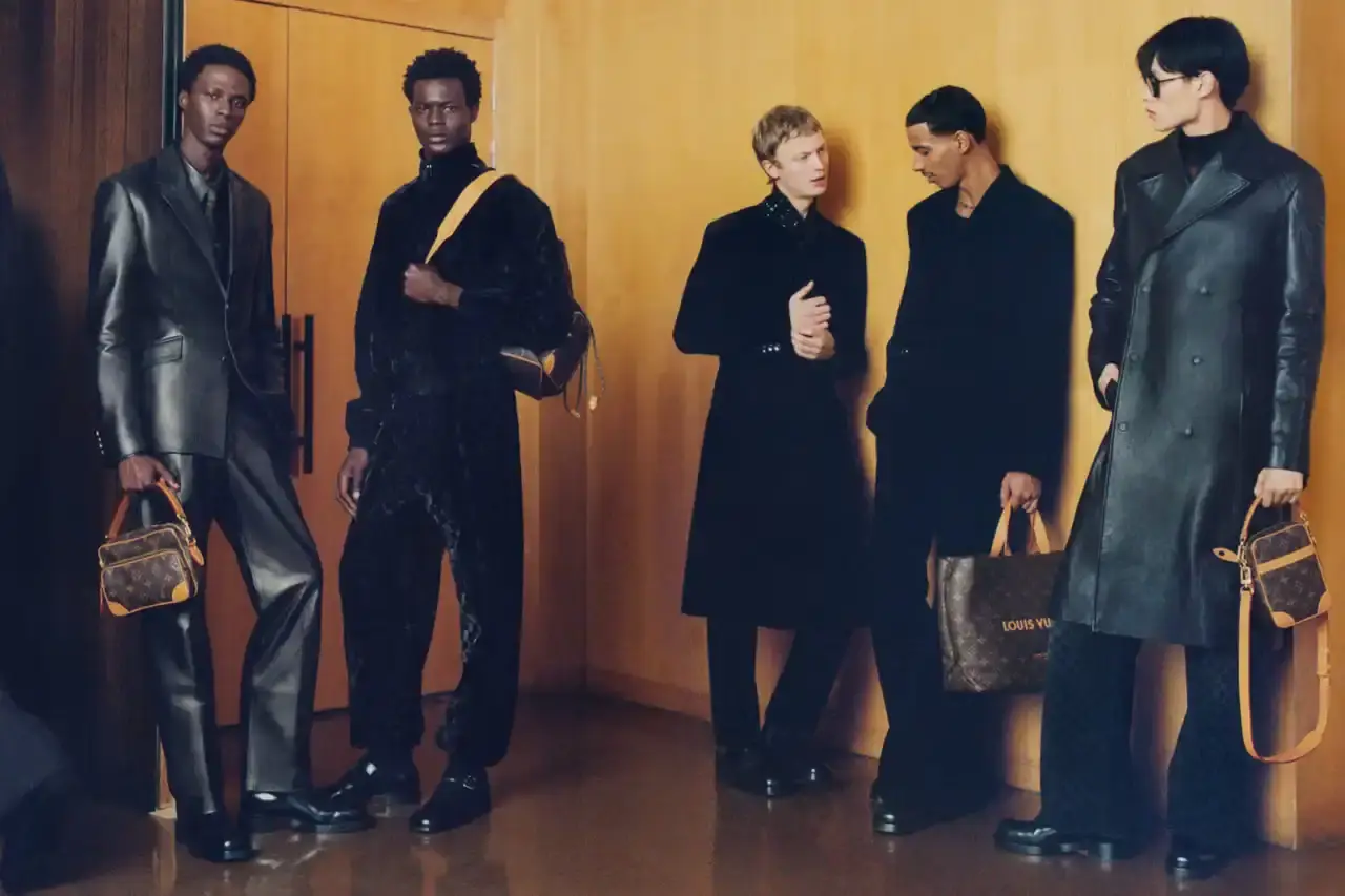 Stef Mitchell Models wearing Louis Vuitton Spring 2025 collection pose in UNESCO's headquarters. They're dressed in earth-toned suits and casual wear, photographed in formal meeting rooms and gardens. The images showcase bags, sunglasses, and diplomatic-inspired fashion against modernist architecture. (image 13 of 15)
