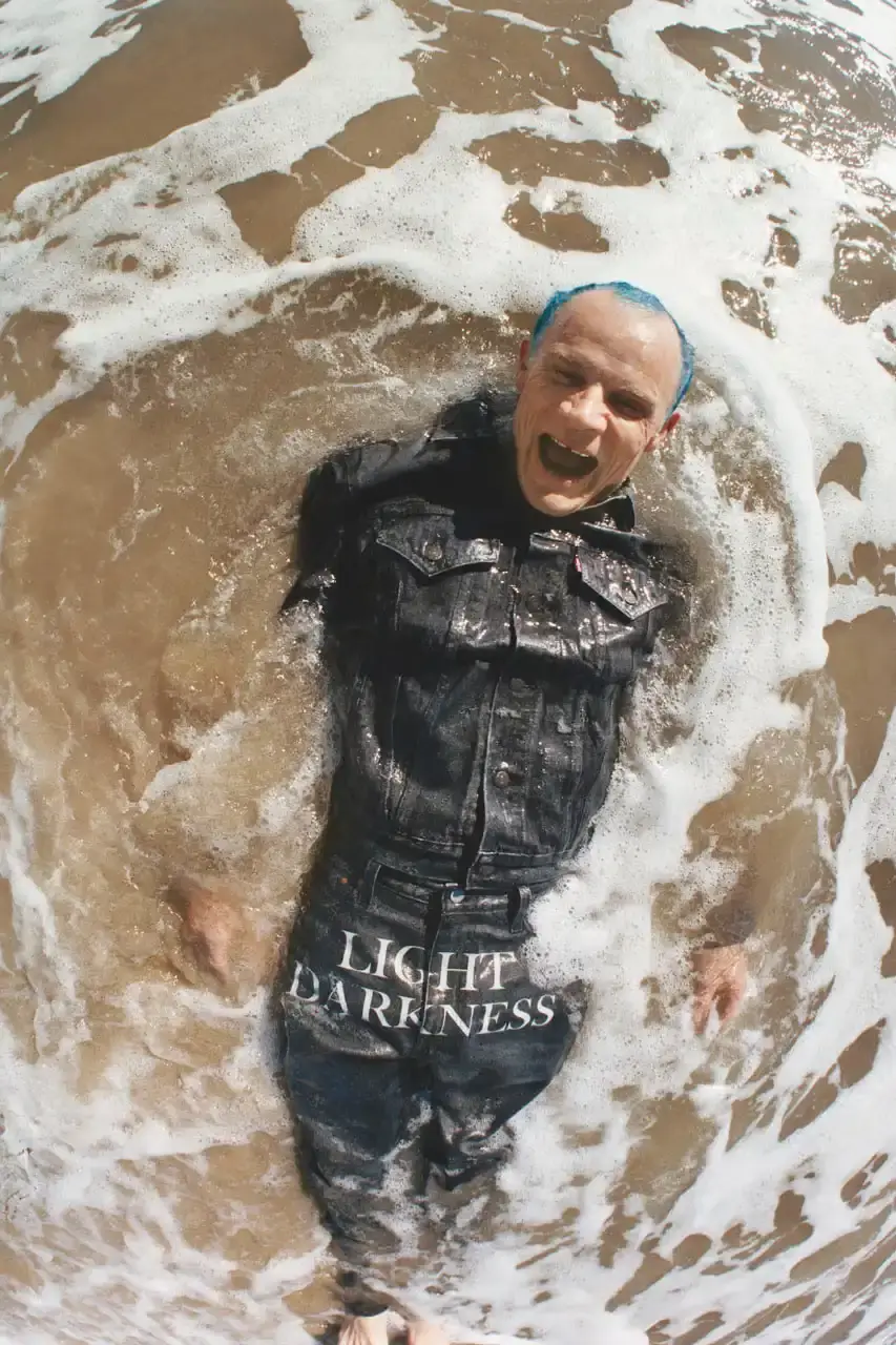 Levi's x UNDERCOVER Flea, bassist of Red Hot Chili Peppers, wearing a dark denim Levi's x UNDERCOVER Pinnacle Type II Trucker Jacket against a neutral background (image 10 of 15)
