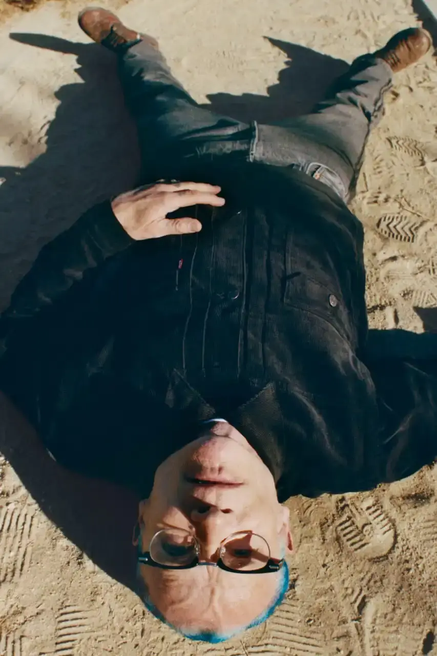 Levi's x UNDERCOVER Flea, bassist of Red Hot Chili Peppers, wearing a dark denim Levi's x UNDERCOVER Pinnacle Type II Trucker Jacket against a neutral background (image 13 of 15)